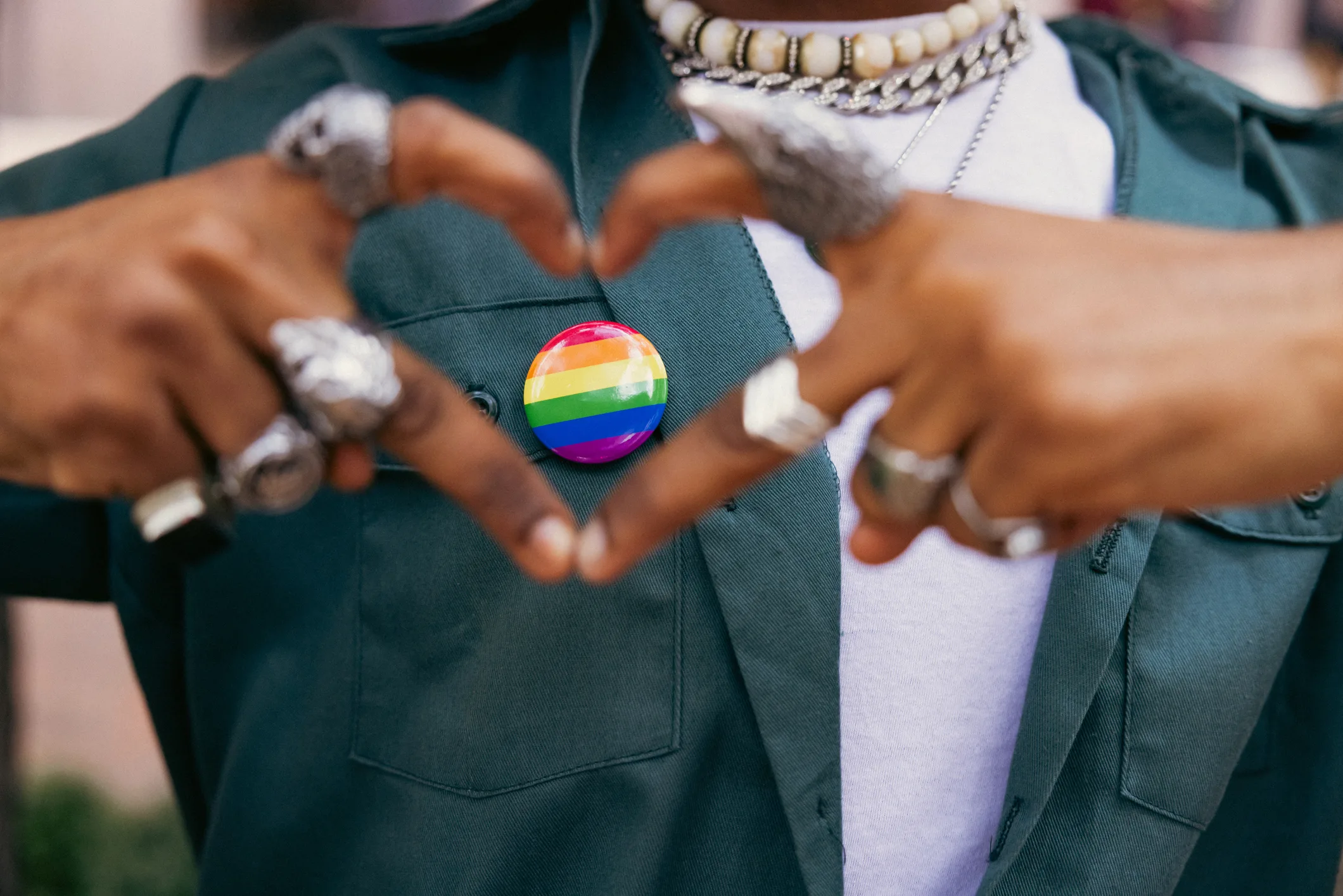 Activist showing heart shape on LGBTQIA+ rainbow pin on his shirt